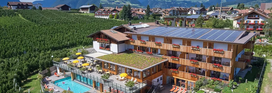 Hotel mit Solarzellen und Pool in einer grünen Berglandschaft