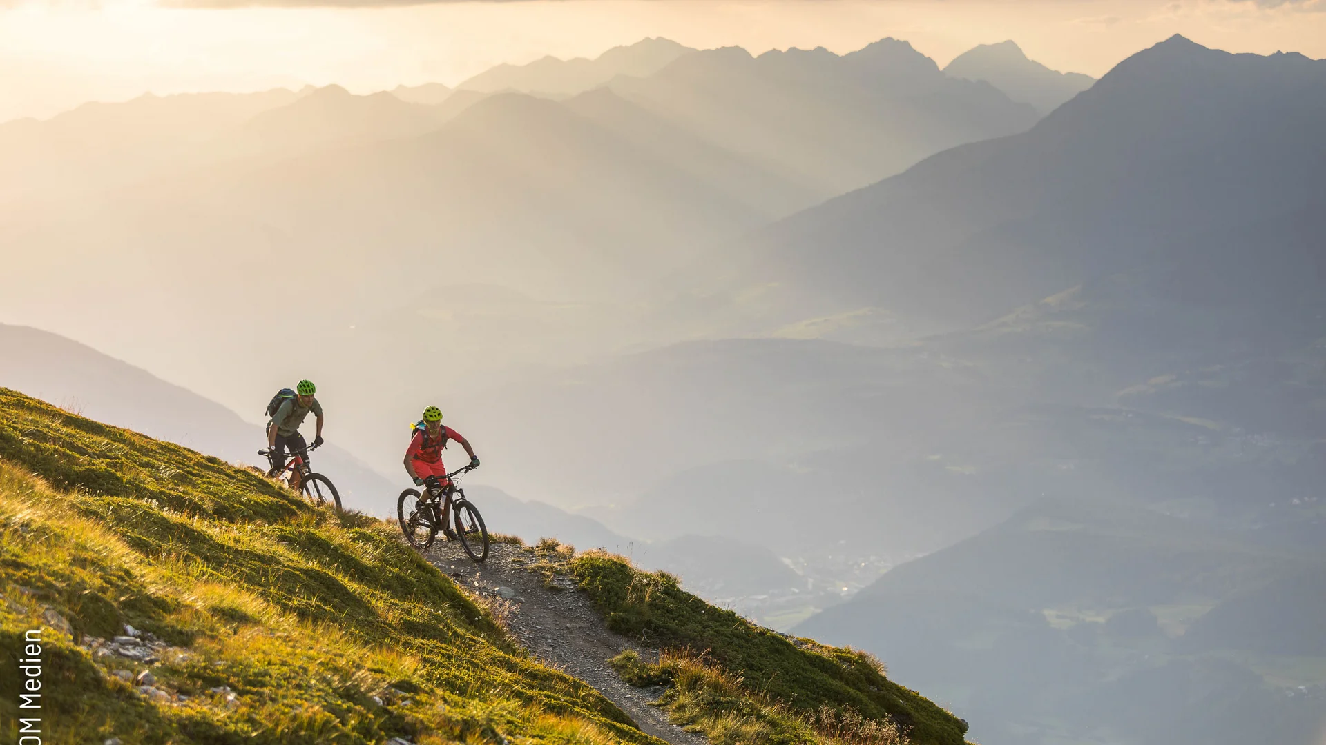Zwei Mountainbiker auf Bergpfad bei Sonnenuntergang