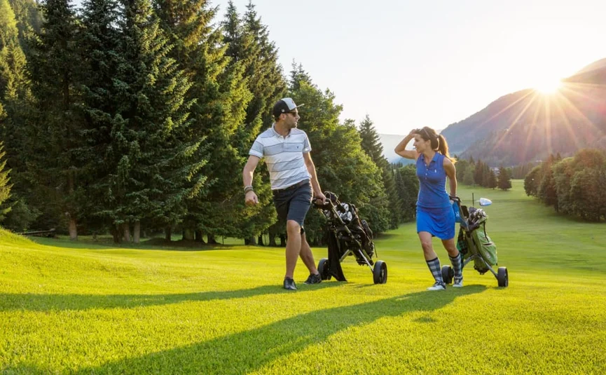 Stay here - Free golf / 2 nights Two golfers walking with golf carts on a sunny golf course