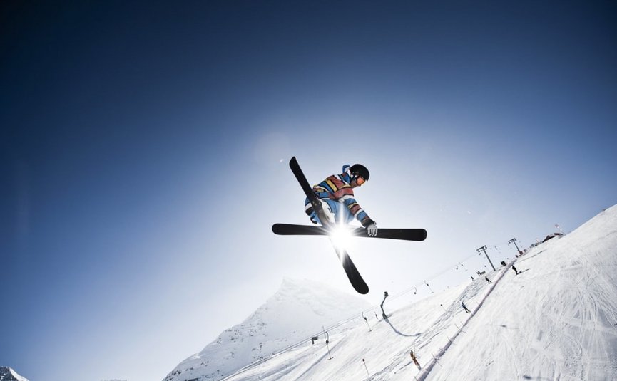 Skier maakt sprong op besneeuwde helling bij zonsondergang