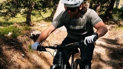 Mann fährt Mountainbike auf Waldweg bei Sonnenschein