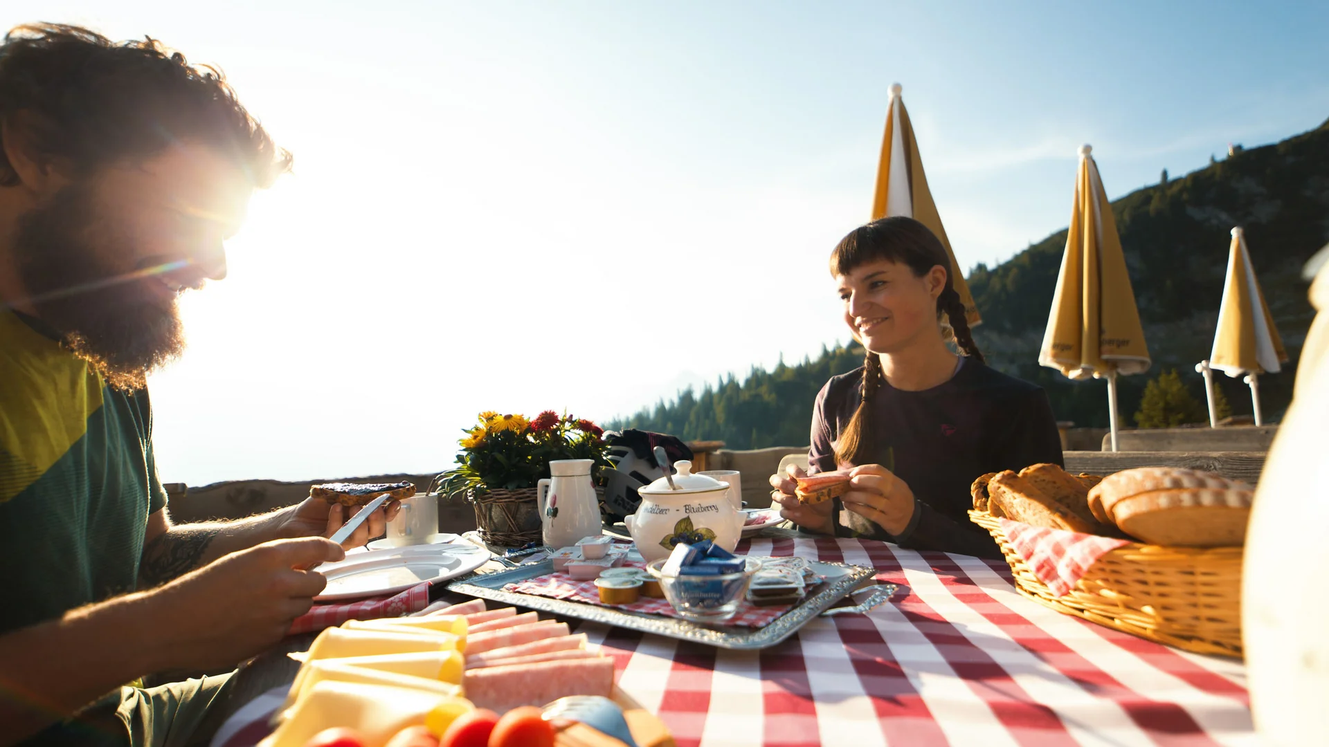 Paar genießt Frühstück im Freien bei sonnigem Bergwetter