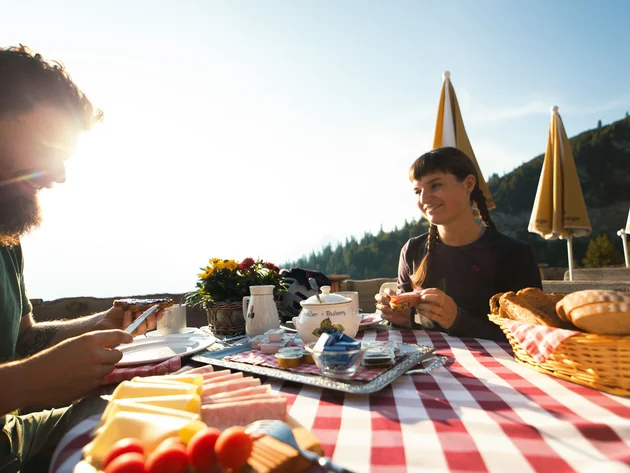 Paar genießt Frühstück im Freien bei sonnigem Bergwetter