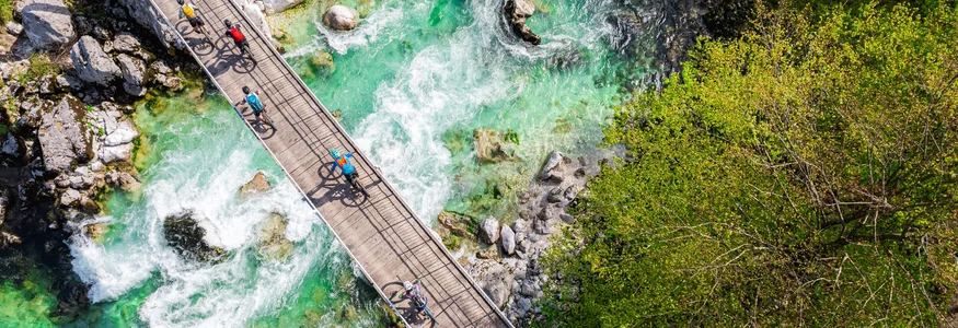 Julische Alpen © Soca Valley - Ziga Koren Radfahrer überqueren eine Brücke über einen klaren, grünen Fluss