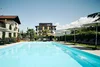 Outdoor swimming pool with loungers and umbrellas in front of a hotel building