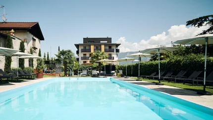 Outdoor swimming pool with loungers and umbrellas in front of a hotel building