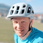 Mann mit blauem Shirt und weißem Fahrradhelm im Freien