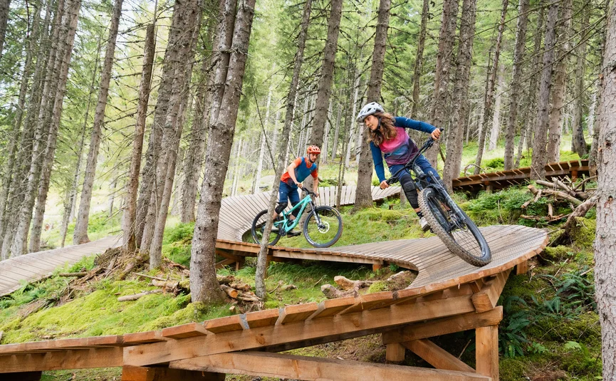 Twee mountainbikers op een houten parcours in het bos