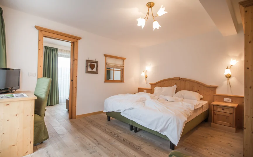 Bright bedroom with wooden furniture and unmade bed
