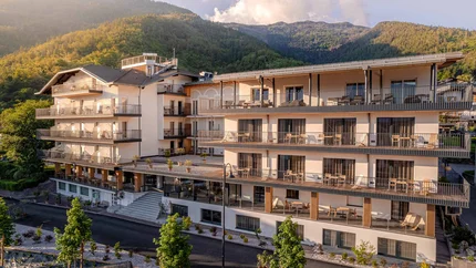 Moderner Hotelkomplex vor bewaldeten Bergen bei Sonnenuntergang