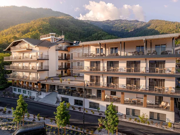 Moderner Hotelkomplex vor bewaldeten Bergen bei Sonnenuntergang