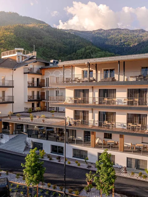 Moderner Hotelkomplex vor bewaldeten Bergen bei Sonnenuntergang