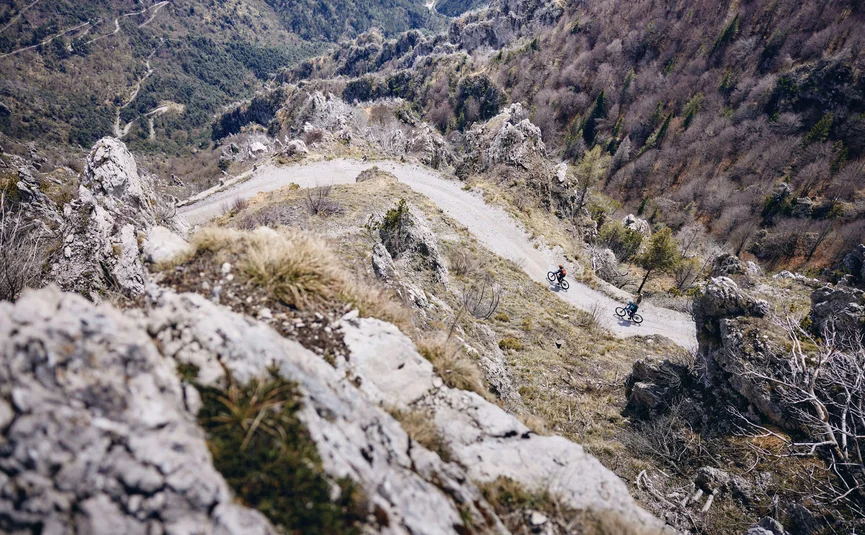 Zwei Radfahrer auf einem kurvigen Bergpfad mit felsiger Landschaft