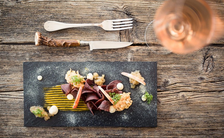 See-Aktivhotel Regitnig - Hotel & Chalets **** © Regitnig GmbH Fein angerichtetes Gericht mit Fleisch, Soßen und Apfelscheiben auf schwarzem Teller