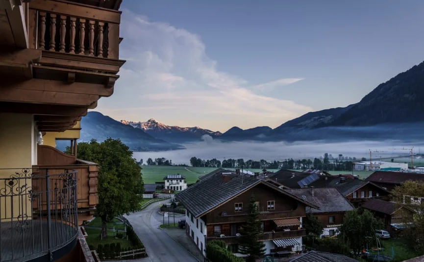 Dorf mit Bergen und Nebel im Tal bei Sonnenaufgang