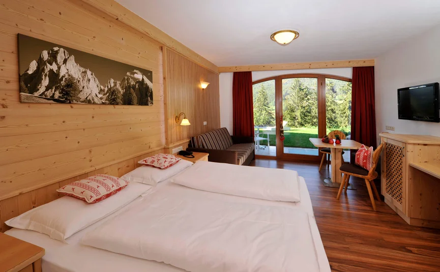 Hotelkamer met houten wanden, tweepersoonsbed en uitzicht op tuin