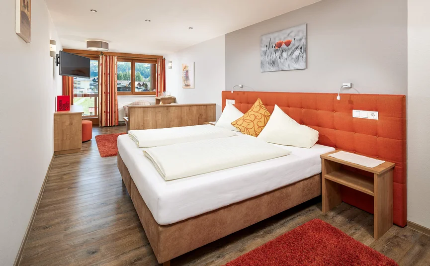 Bright hotel room with orange headboard and modern wooden flooring