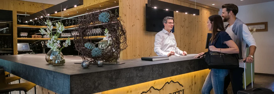 Paar checkt an der Rezeption des Alpinhotels ein