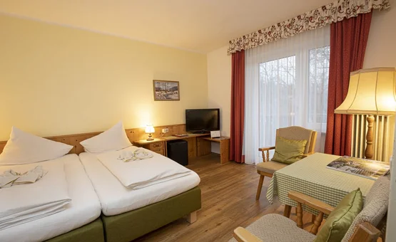 Cozy hotel room with two beds, TV, table, and chairs