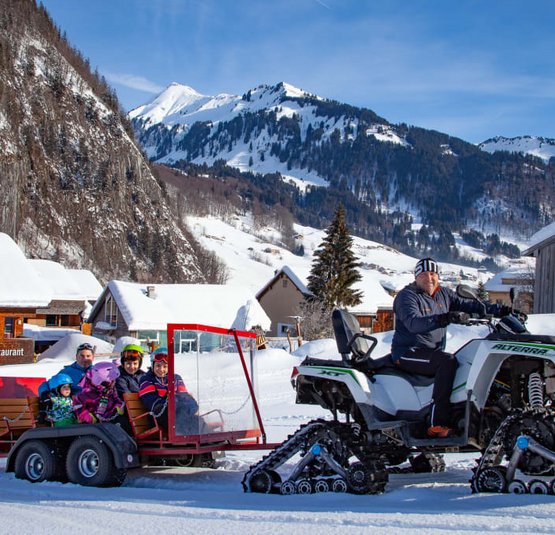 CHILDREN´S SNOW Snowmobile pulling trailer with family in snowy mountain village