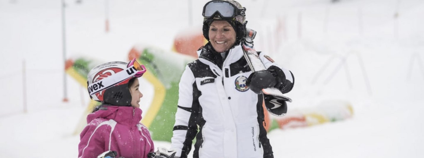 Volwassene en kind met ski's glimlachend in de sneeuw