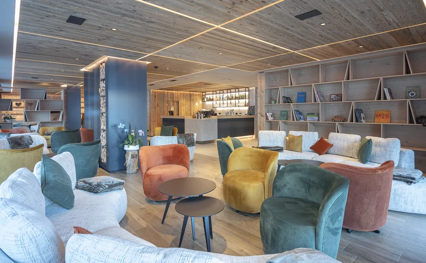 Moderner Lounge-Bereich mit bunten Sesseln und gemütlichen Sofas in hellem Holzinterieur