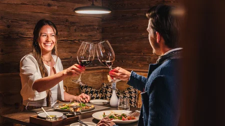 Paar stößt bei romantischem Abendessen in rustikalem Restaurant mit Wein an