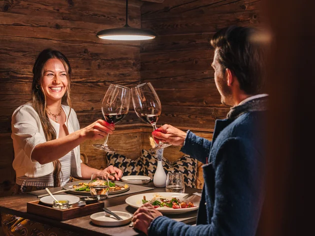Paar stößt bei romantischem Abendessen in rustikalem Restaurant mit Wein an