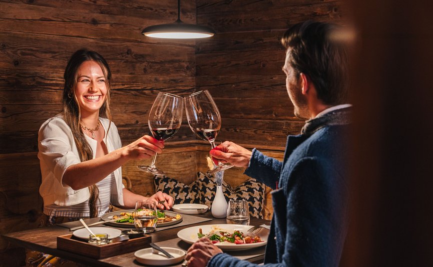 Hotel Arpuria | Hidden Luxury Mountain Home **** © Brandnamic Paar stößt bei romantischem Abendessen in rustikalem Restaurant mit Wein an