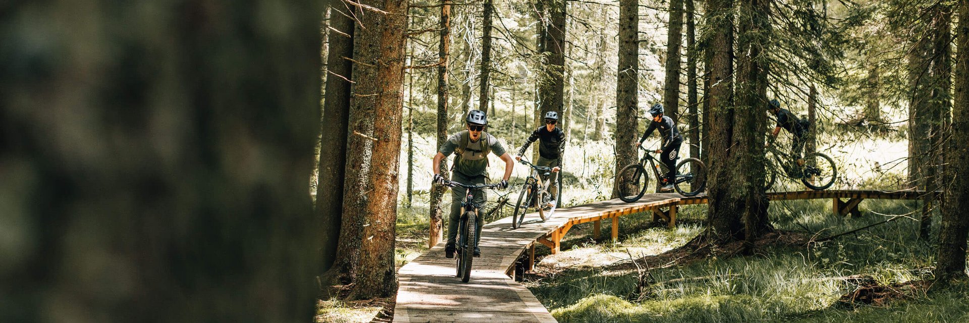 Hotel Planja **** © Denis Janežič, Unitur Vier Mountainbiker fahren auf einem Holzsteg durch einen Wald