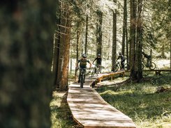 Rogla - Pohorje © Denis Janežič, Unitur Four mountain bikers ride on a wooden trail through a forest