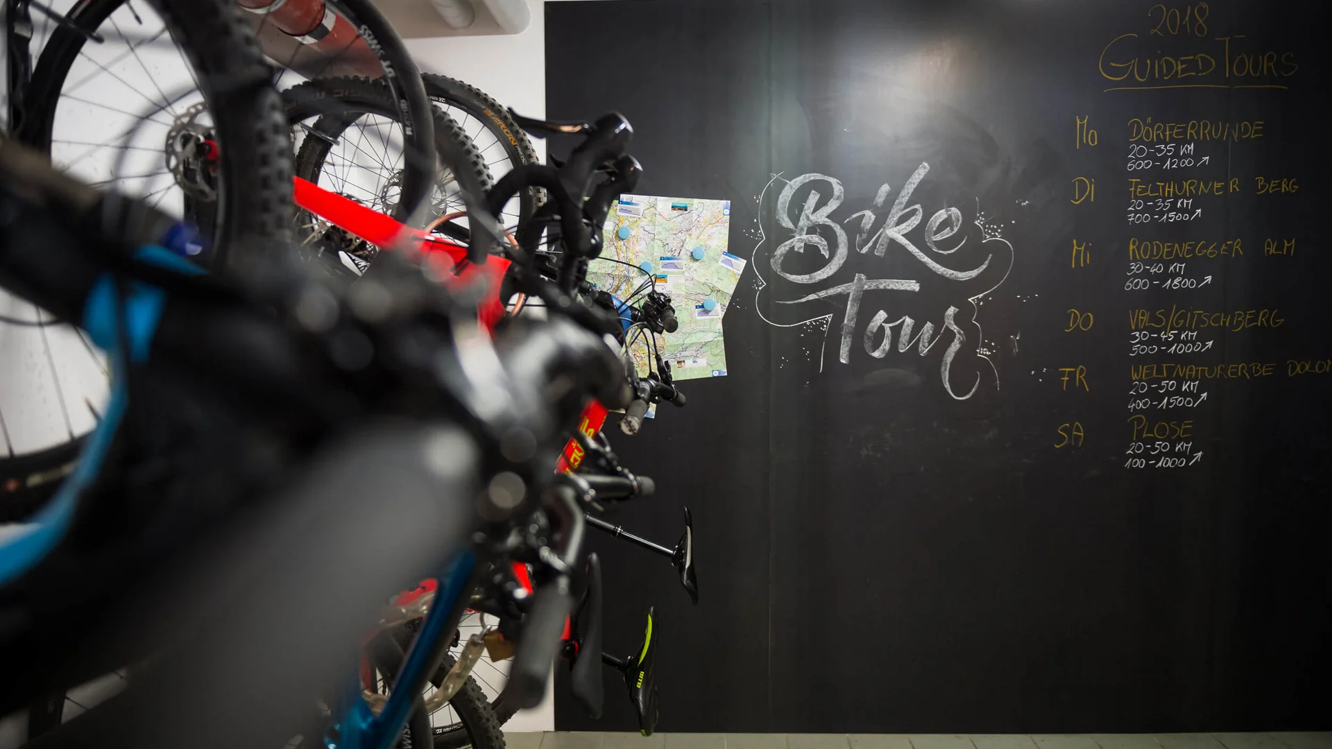 Mountainbikes vor einer Tafel mit Tourplan und Karten für geführte Bike-Touren