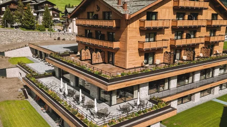 Modernes Holzhotels mit Schwimmbad und grünen Bergen im Hintergrund