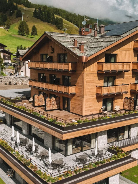 Modernes Holzhotels mit Schwimmbad und grünen Bergen im Hintergrund