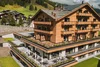 Modern wooden hotel with pool and green mountains in the background