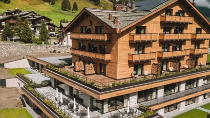 Modern wooden hotel with pool and green mountains in the background