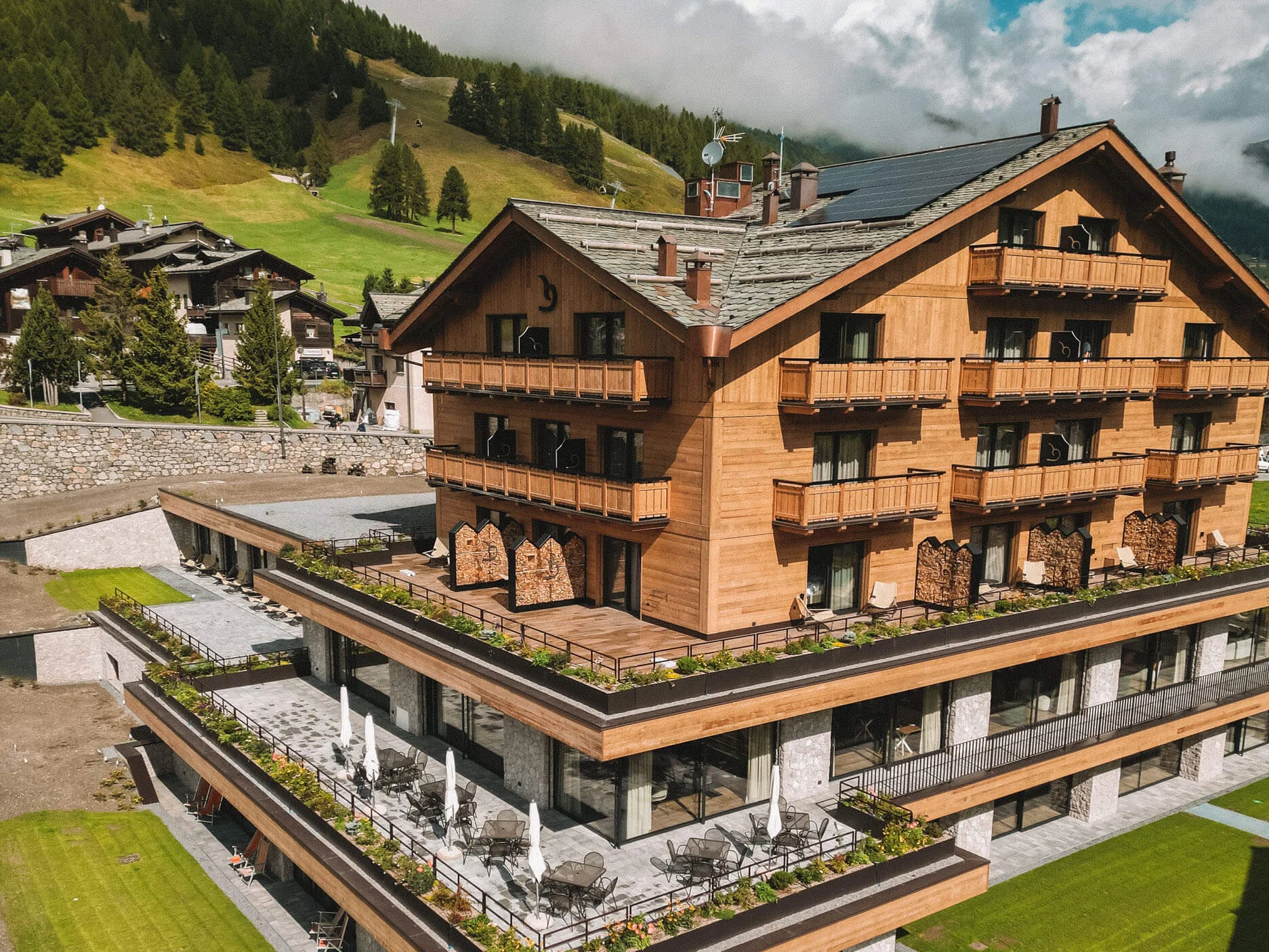 Modern houten hotel met zwembad en groene bergen op de achtergrond