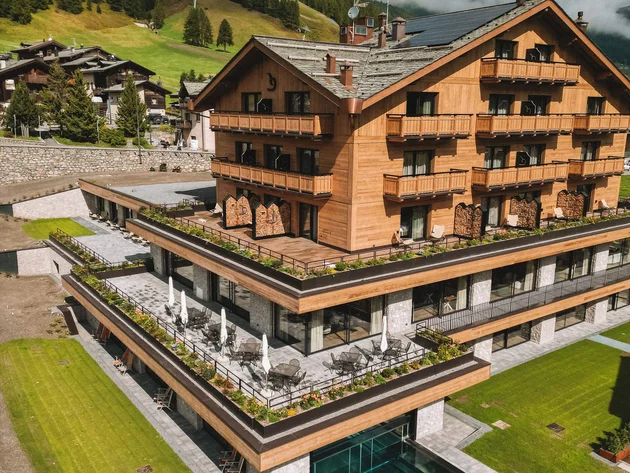 Modernes Holzhotels mit Schwimmbad und grünen Bergen im Hintergrund