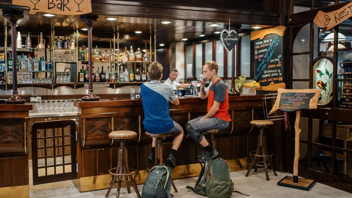 9 Gründe, warum Kočevsko noch ein echter MTB-Geheimtipp ist
© David Karg Zwei Männer sitzen an einer Bar mit Rucksäcken auf dem Boden
