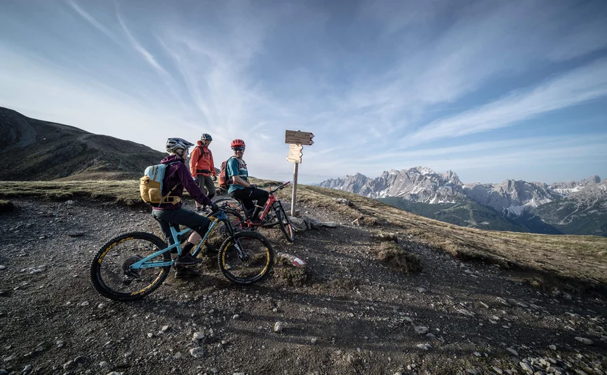 Mountainbike-Urlaub in der Region 3 Zinnen Dolomites © Tourismusverein Sexten - Dennis Stratmann Drei Mountainbiker an einem Wegweiser mit Bergblick im Hintergrund