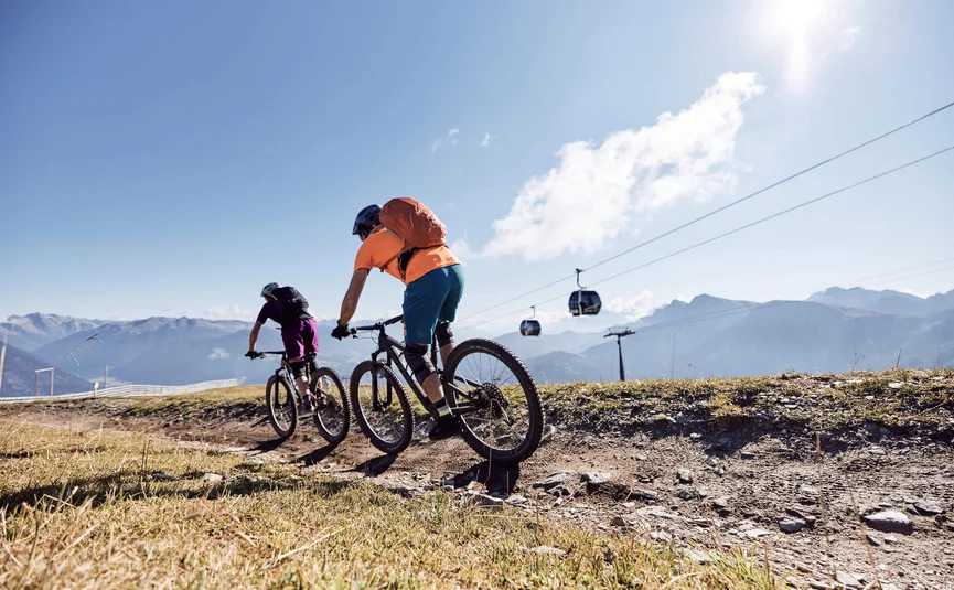 Zwei Fahrradfahrer fahren auf einem Bergweg bei sonnigem Wetter