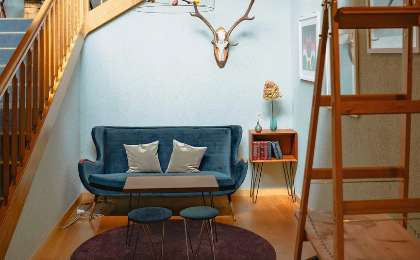 Gemütliche Sitzecke unter einer Holztreppe mit Hirschgeweih an der Wand