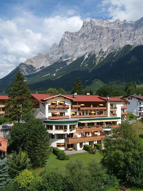 Bergdorf mit Häusern vor steinigem Berg unter blauem Himmel mit Wolken