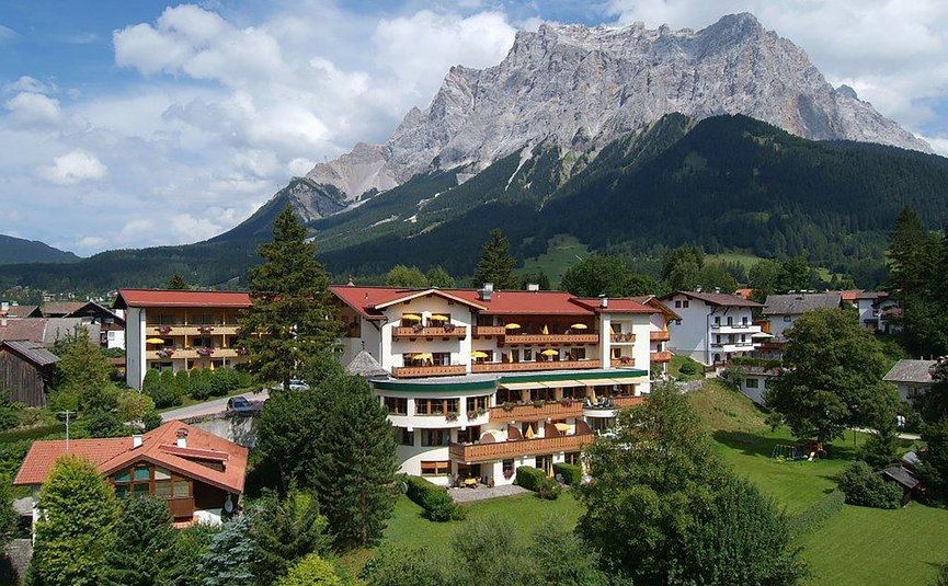 Sporthotel Schönruh **** © Sporthotel Schönruh Mountain village with houses beneath rocky peak under blue sky with clouds