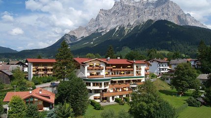 Bergdorf mit Häusern vor steinigem Berg unter blauem Himmel mit Wolken