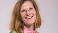 Lächelnde Frau in Mountainbike-Trikot und Jeans vor hellem Hintergrund