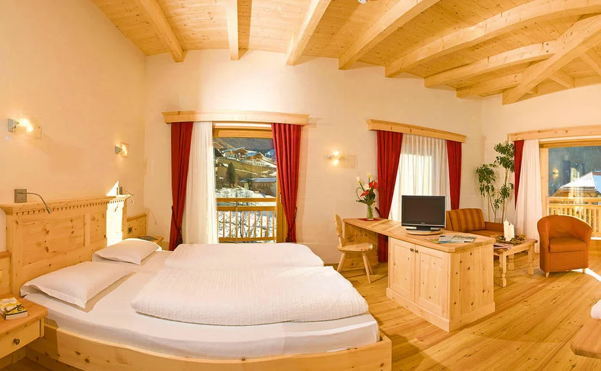 Helles Hotelzimmer mit Holzmöbeln, Doppelbett und Bergblick durch Fenster