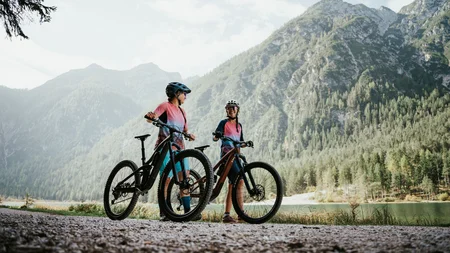 Twee fietsers in kleurrijke kleding met helmen bij bergmeer