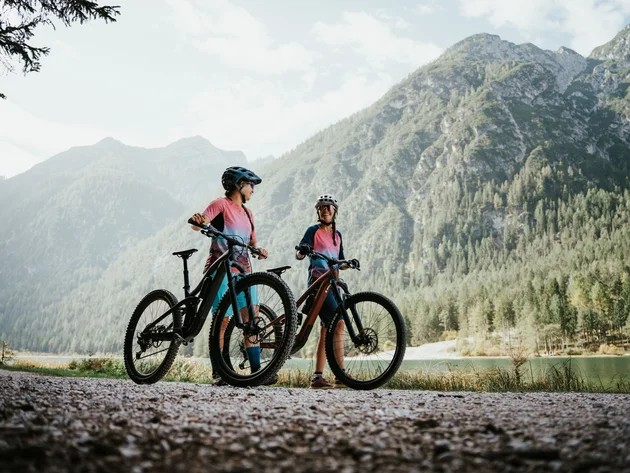 Twee fietsers in kleurrijke kleding met helmen bij bergmeer