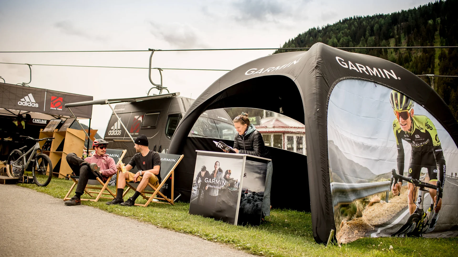 Zwei Männer sitzen vor einem Garmin-Zelt an einem Outdoor-Event